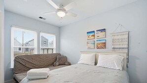 Une chambre à coucher avec un lit, un ventilateur de plafond et une fenêtre avec des stores.