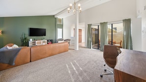 A modern living room with a sectional sofa, a flat-screen TV, and a dining area with a table and chairs. - Albuquerque Escape Hot Tub + Atrium 4 Bedroom Home (Albuquerque)