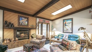 A cozy living room with a fireplace, patterned furniture, and a large poster on the wall. - H5 Meadow Creek 3 Bedroom Townhouse (Vail)