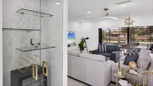 A modern living room with a sofa, a glass display cabinet with wine glasses, and a telescope. - Port Charlotte 4 Bedroom Pool Vacation Home on Peace River 4 Home (Port Charlotte)
