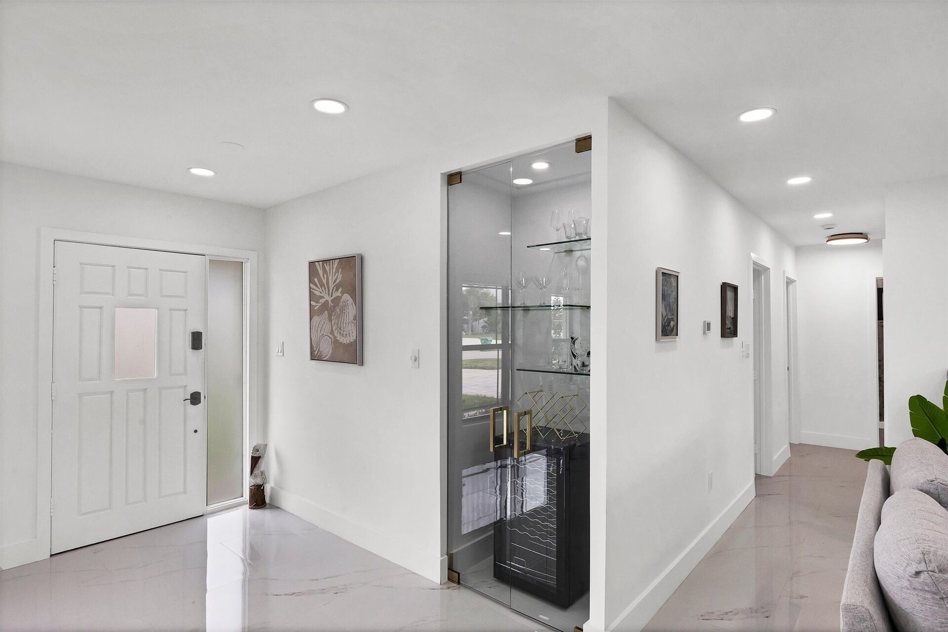 A hallway with a white door, a glass display case, and a plant.