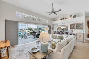 A spacious living room with a large sofa, a dining area, and a kitchen. - Punta Gorda Isles Private Pool Vacation Home - Waterfront Canal Views 4 Bedroom Home (Punta Gorda)