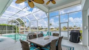 A covered outdoor area with a pool, wicker furniture, and a view of a residential area. - Punta Gorda Isles Private Pool Vacation Home - Waterfront Canal Views 4 Bedroom Home (Punta Gorda)