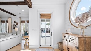 A modern living room with a sofa, a wooden cabinet, and a large window with a view of the outdoors. - Beach Bike Cottage 5 Bedroom, King Beds, Coastal Luxury Living, EV Charger (Seacrest Beach)