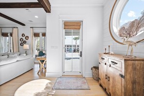 A modern living room with a sofa, a wooden cabinet, and a large window with a view of the outdoors. - Beach Bike Cottage 5 Bedroom, King Beds, Coastal Luxury Living, EV Charger (Seacrest Beach)