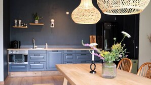 A modern kitchen with grey cabinets, a wooden dining table, and a vase with flowers.