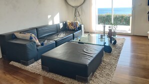 A modern living room with a sectional sofa, a glass coffee table, and a view of the sea through large windows. - Bella vista (Santa-Maria-di-Lota)