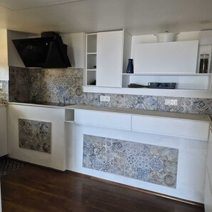 A kitchen with patterned tiles, white cabinets, and a black range hood. - Bella vista (Santa-Maria-di-Lota)