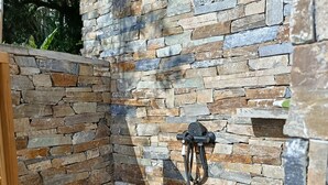 A stone-walled outdoor area with a wooden floor and a metal structure. - Bella vista (Santa-Maria-di-Lota)