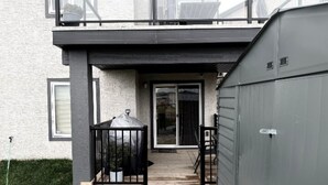 Ein modernes, zweistöckiges Haus mit überdachter Terrasse, Garage und einer sichtbaren Tür zum Innenbereich.