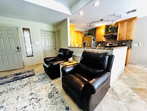 A living room with two leather sofas, a coffee table, and a patterned rug. - Coastal escape/pool/pickleball/pets/tennis/golf/beach & fun (Laguna Vista)