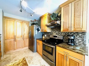 A kitchen with wooden cabinets, a stainless steel refrigerator, a stove, and a coffee maker. - Coastal escape/pool/pickleball/pets/tennis/golf/beach & fun (Laguna Vista)