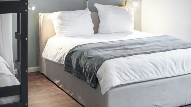 Un dormitorio moderno con una cama litera, una mesita de noche con lámpara y tres obras de arte abstracto en la pared.