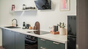 Una cocina moderna con un refrigerador negro, un horno empotrado, un lavamanos y una encimera con diversos electrodomésticos y elementos decorativos.