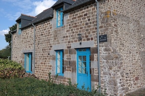 A stone building with blue windows and doors, a sign indicating a historical site, and a small garden area in front. - Breton country house 35 minutes from Mont Saint Michel. Pets welcome! (Saint-Rémy-du-Plain)