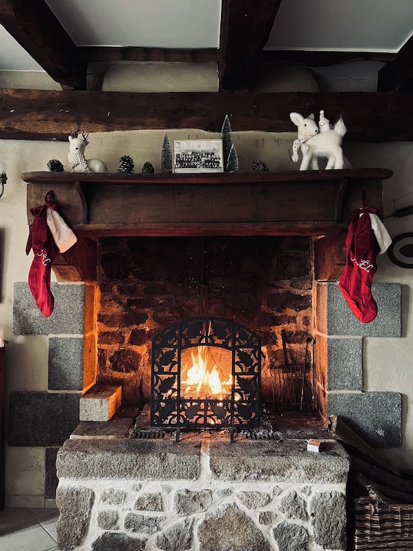A stone fireplace with a fire, flanked by red stockings, and a shelf above with decorative items. - Breton country house 35 minutes from Mont Saint Michel. Pets welcome! (Saint-Rémy-du-Plain)
