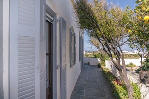 A narrow stone pathway leading to a white building with shutters, surrounded by greenery and a view of the sea. - Kypseli House - Quiet Garden Home for Families & Groups, steps from Apollonia (Apollonia)