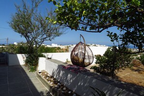 Una terraza en la azotea con un sillón colgante, una pared blanca y vistas al mar y a los edificios.