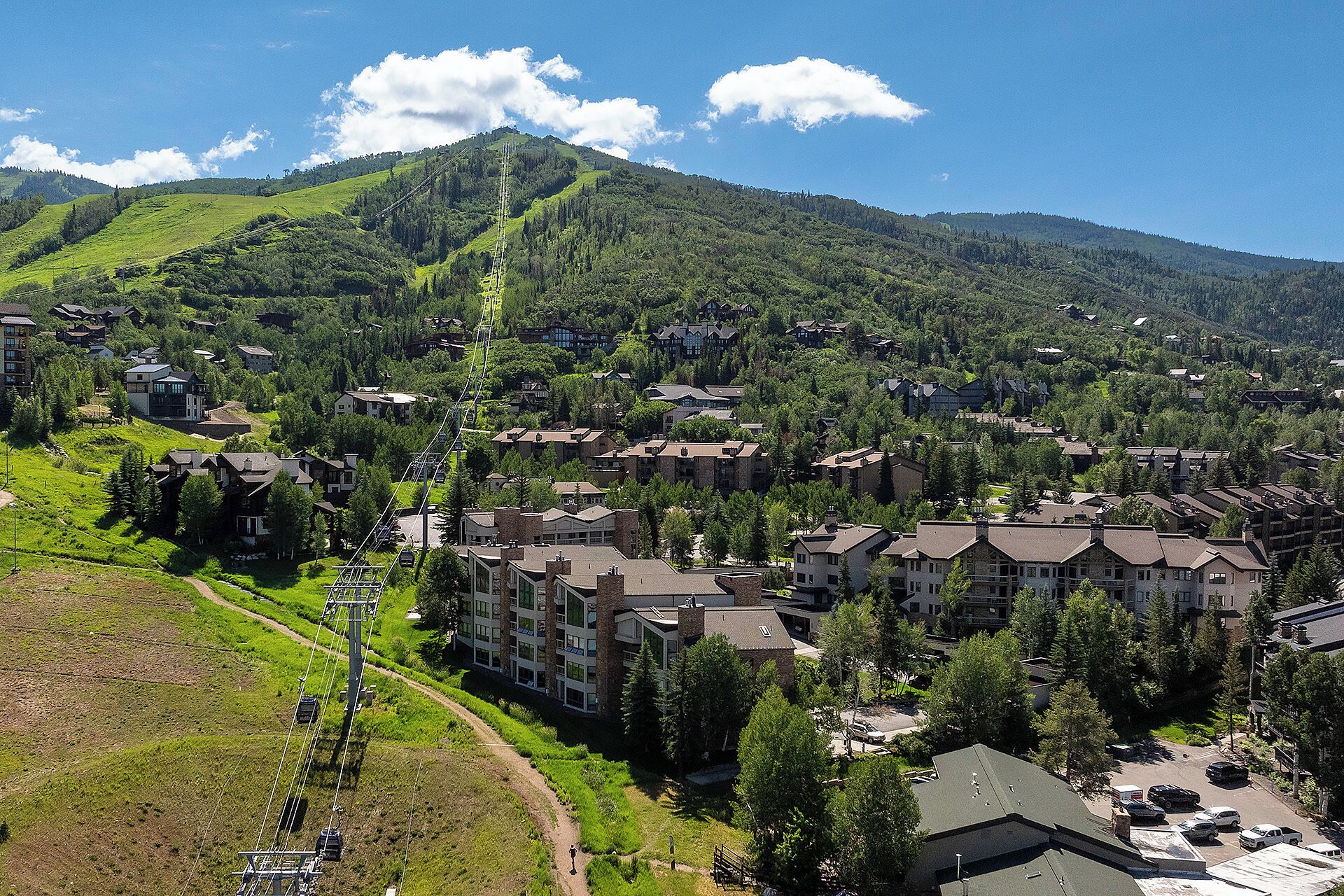 A residential area with multi-story buildings, a ski lift, and a mountainous backdrop.