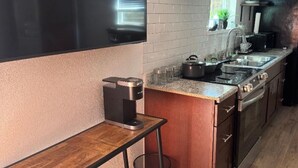 Eine moderne Küche mit Einbauofen, Kaffeemaschine und einem Fenster mit Jalousien.
