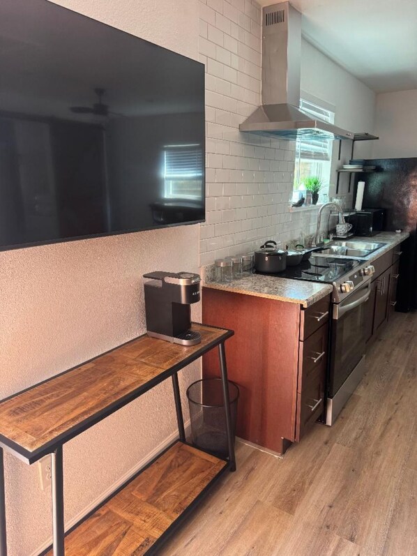 Una cocina moderna con horno integrado, cafetera y ventana con persianas.