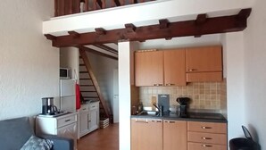 A compact living space with a kitchenette, a sofa, and a staircase leading to an upper level. - Exceptional stay in Corsica - Air-conditioned apartment with sea view in Bravone (Linguizzetta)