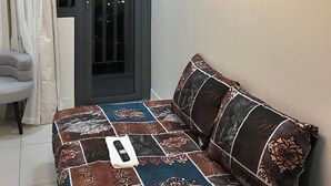 Een slaapkamer met een bed, een stoel, een deur en een spiegel aan de muur.