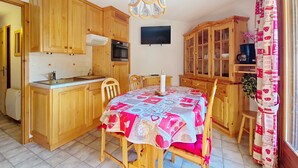 Een keuken met houten kastjes, een eettafel met een tafelkleed met een patroon en een kroonluchter.