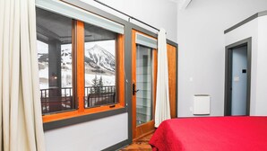 A room with a bed, a window with a view of mountains, and a door leading to an outdoor balcony. - Eagle's Nest |3 Bedroom | Free Shuttle| Garage | Shared Hot Tub |  Mtn Views (Mt. Crested Butte)