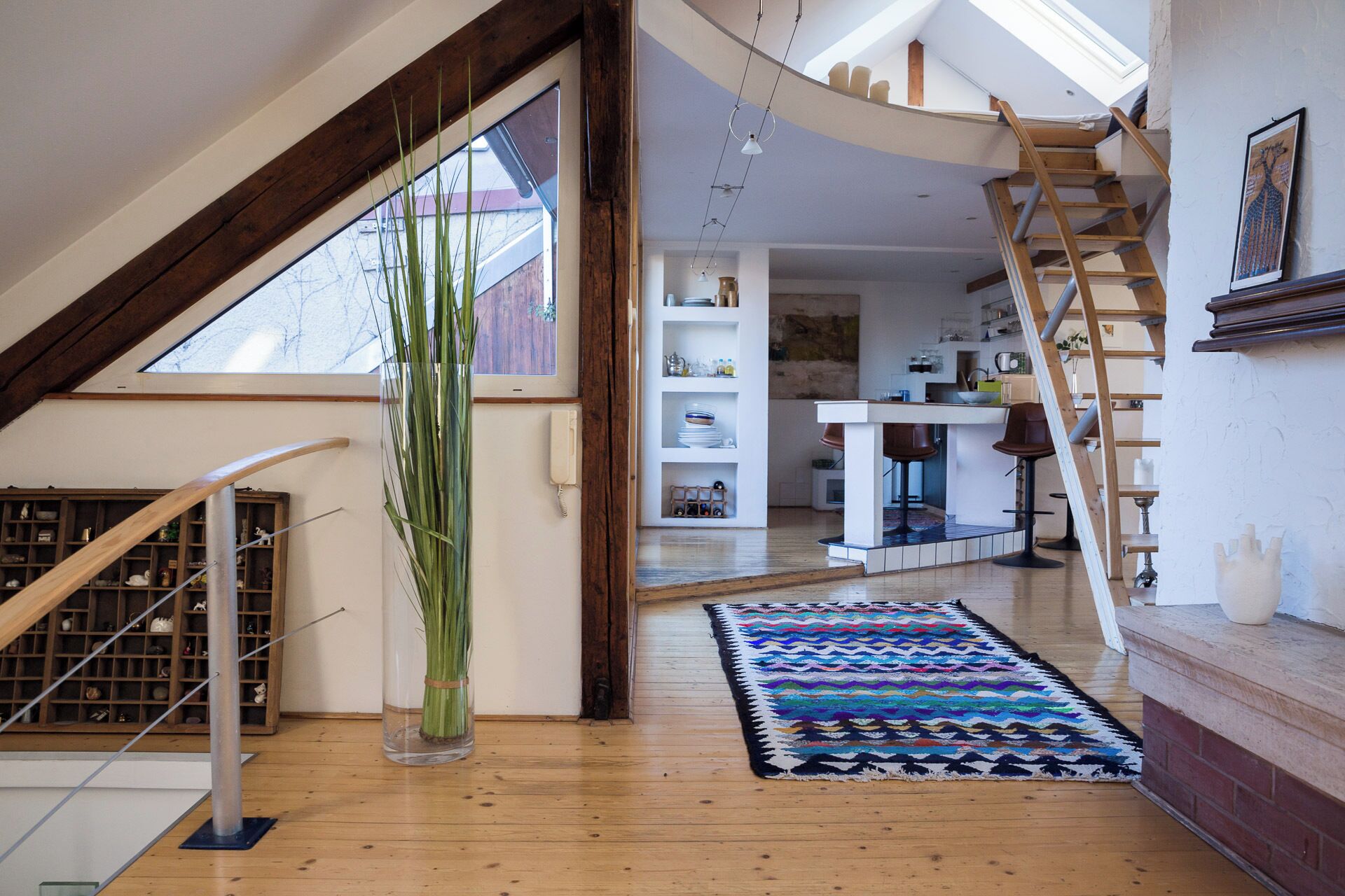 Un loft amplio con escalera de madera, comedor y vista al exterior.