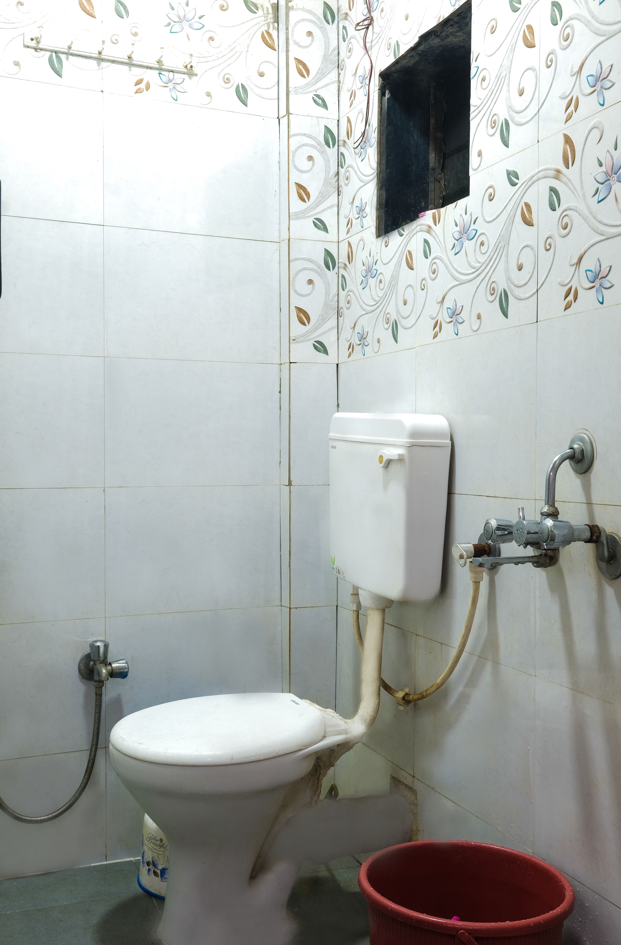 Un baño con inodoro, ducha y un cubo rojo.