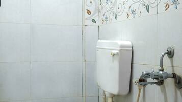Un baño con inodoro, ducha y un cubo rojo.