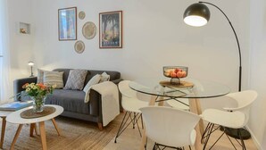 Una sala de estar moderna con un sofá, una mesa de centro, sillas, una lámpara de pie y decoración en la pared.