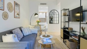 Una sala moderna con sofá, mesa de centro y mueble de televisión con estantes.