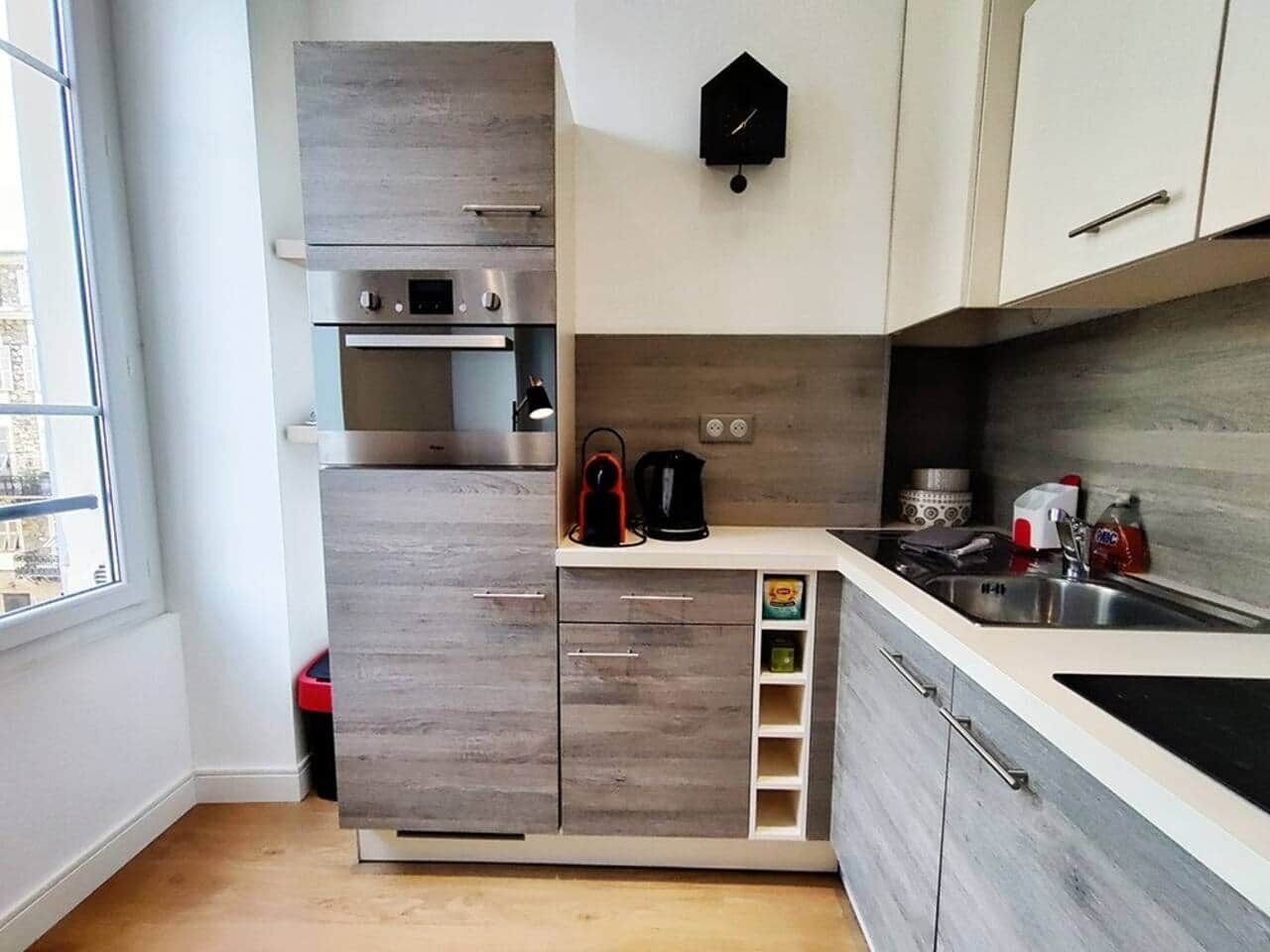 A compact kitchen with a built-in oven, a coffee maker, and a sink.