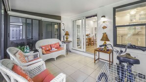 A spacious balcony with wicker furniture, a bicycle, and a sliding glass door leading to an indoor dining area. - Centrally located townhouse w/ heated pool & spa (Marco Island)