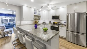 A modern kitchen with white cabinets, a stainless steel refrigerator, and a granite countertop. - Centrally located townhouse w/ heated pool & spa (Marco Island)