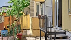 A narrow alleyway with a small staircase leading to a door, surrounded by buildings with balconies and potted plants. - Cozy ground-floor mini apartment a few meters from Rimini's dockyard (Rimini)