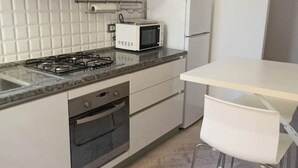A modern kitchen with a gas stove, microwave, oven, and white cabinets. - Cozy ground-floor mini apartment a few meters from Rimini's dockyard (Rimini)