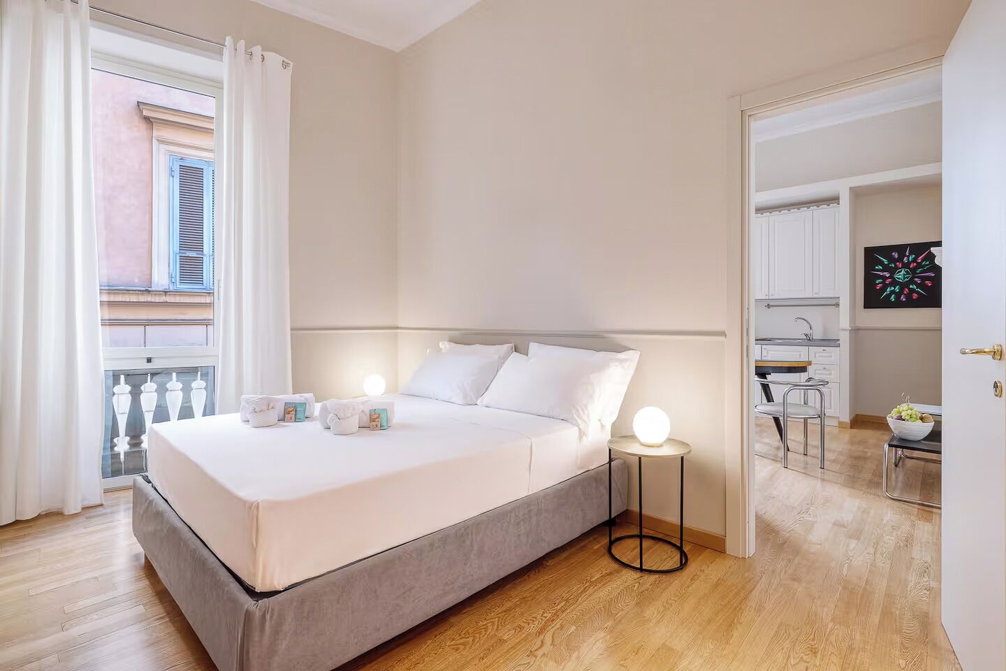 Un dormitorio con cama, mesitas de noche, ventana con cortinas y vistas al exterior.