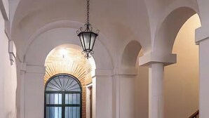 A hallway with a wooden floor, white walls, and a black door with a glass panel. - Navona Boutique House (Rome)