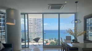 A spacious living room with a large sliding glass door leading to a balcony with a view of the ocean and buildings. - Grand Marina Oceanview Apartments by Xarm Apartments (Santa Marta)