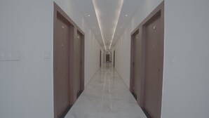 Um corredor comprido e estreito, com piso brilhante, ladeado por portas em ambos os lados.