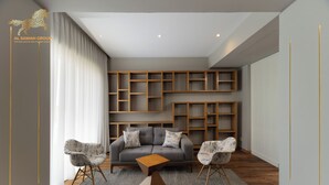 Ein modernes Wohnzimmer mit einem grauen Sofa, zwei gemusterten Sesseln, einem Holztisch und integrierten Holzbögen.