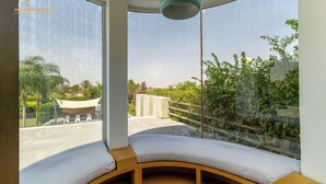 Ein modernes Zimmer mit großen Fenstern, einer hölzernen Bank und einer hängenden Leuchte.