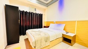 Ein Hotelzimmer mit Bett, Nachttisch und Kleiderschrank.