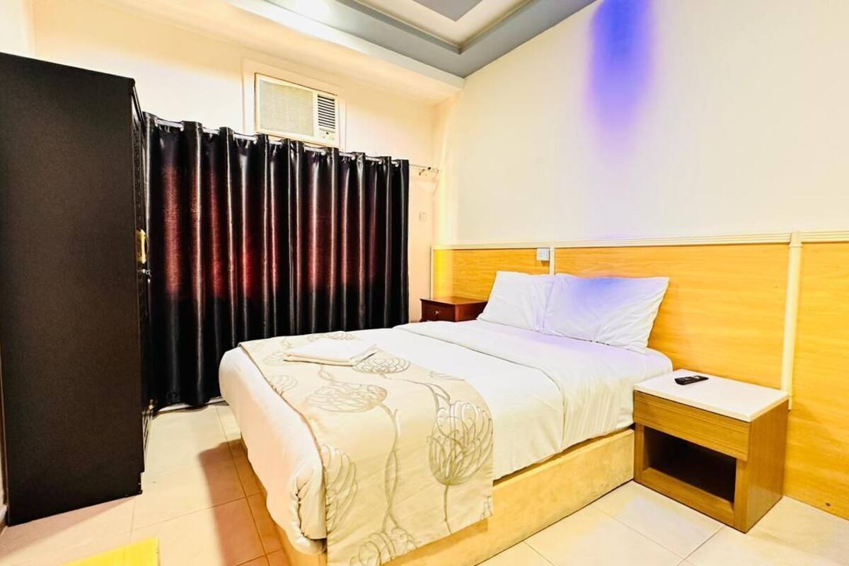 Une chambre d’hôtel avec un lit, une table de chevet et une armoire.