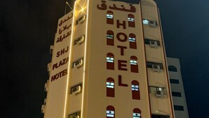 Ein mehrstöckiges Hotel mit beleuchteter Beschilderung, einem markanten Eingang und einer sichtbaren Treppe, die zum Eingang führt.