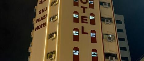 A multi-story hotel with illuminated signage, a prominent entrance, and a visible staircase leading to the entrance.