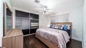 Un dormitorio con cama, ventilador de techo, armario y un banco empotrado.